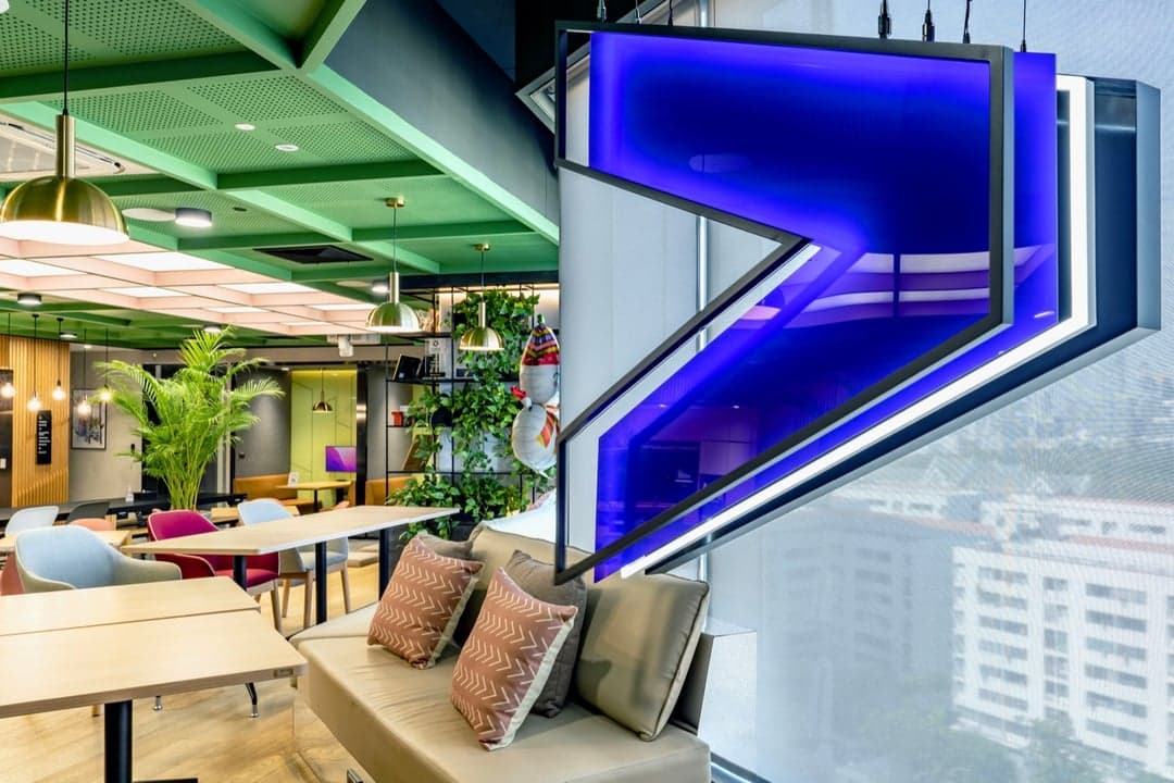 Illuminated brand signage above seating in an airport lounge