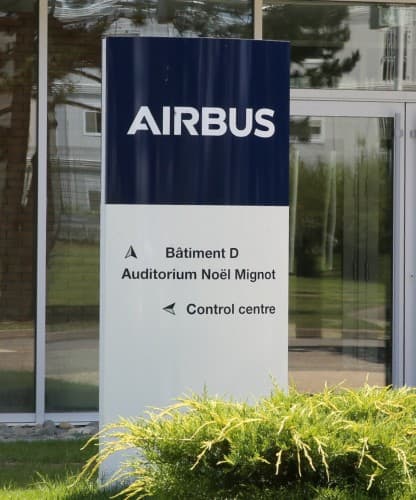 A large blue Airbus wordmark sign mounted on a building wall.