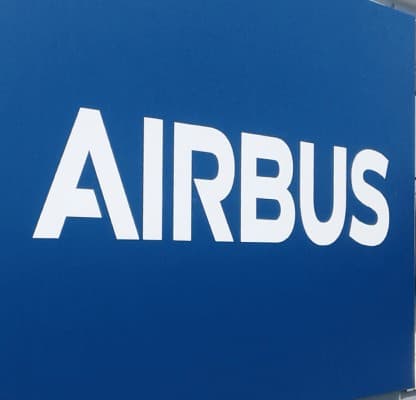 An Airbus site totem sign listing building directions, beside a glazed entrance.