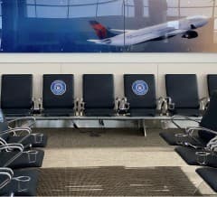 Empty gate seating in front of a wall graphic showing a Delta aircraft in flight.