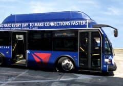 A Delta-branded airport shuttle bus, its livery reading “working hard every day to make connections faster”.