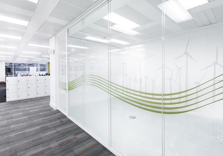 Glass office partitions etched with a green wind-turbine and line-graphic pattern.