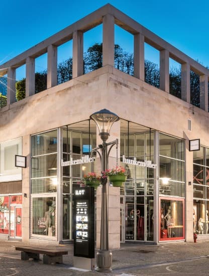 The ILOT corner building at dusk, its shopfronts lit beneath the colonnade.
