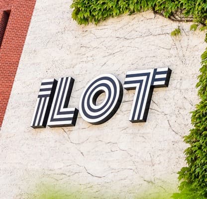 Dimensional ILOT lettering on a rendered wall beside a wall of ivy.