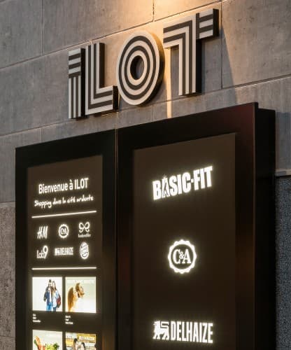 An illuminated ILOT wayfinding totem listing the centre's retailers.