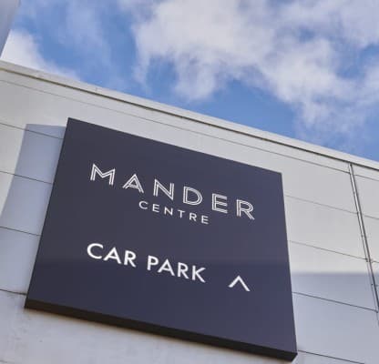 The Mander Centre car park sign on the elevation against a blue sky.