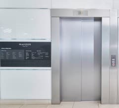 A Mander Centre wayfinding panel beside the elevators in an elevator lobby.