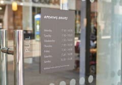 Opening hours listed on a decal beside the Mander Centre entrance door.