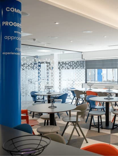 A breakout area with a Pharmanovia-branded column and patterned glass partitions.