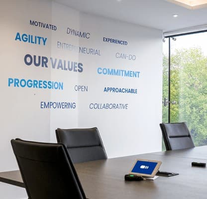 A meeting room wall printed with Pharmanovia's values in blue lettering.