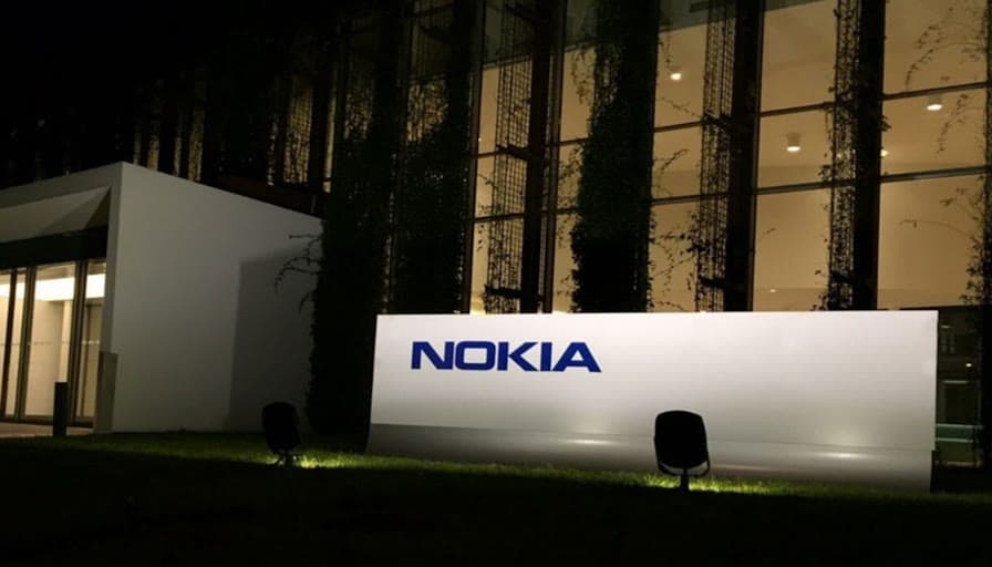 The Nokia wordmark lit on a monolith outside an office at night.