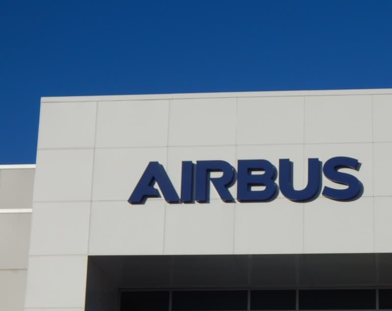 The Airbus wordmark on a building facade against a clear blue sky.