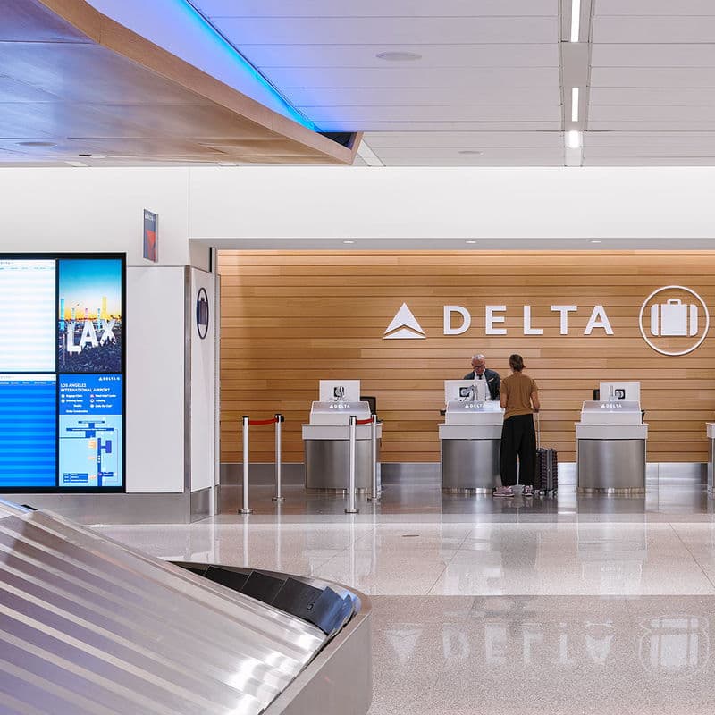 A Delta baggage service office beside the carousel, its counter under an illuminated Delta wordmark.