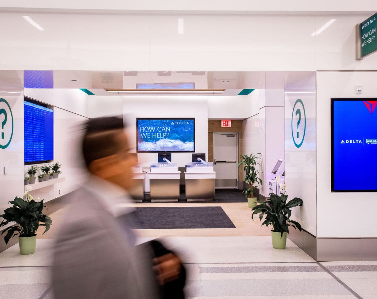 Passengers at a Delta help center, digital screens on either side of the entrance.