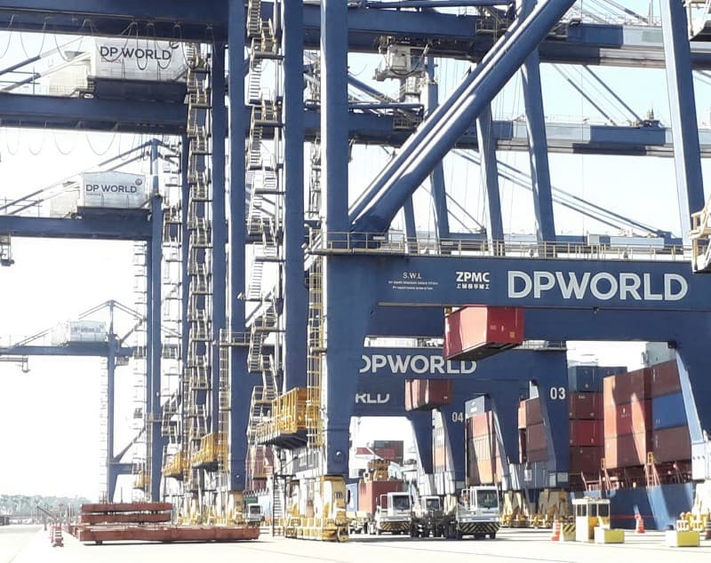 DP World ship-to-shore cranes at Santos, the wordmark lettered across their gantries above stacked containers.