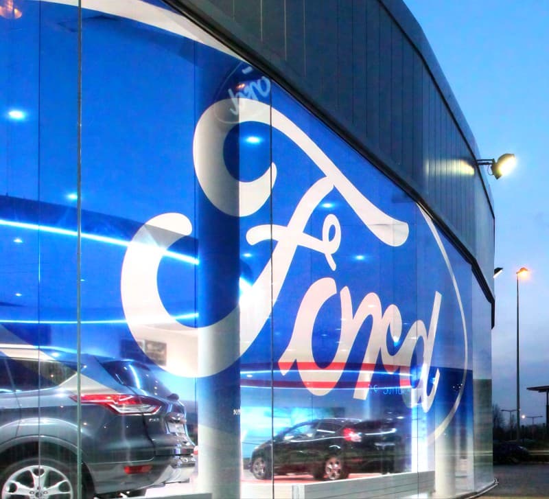 The Ford script applied in large format across a showroom's curved glass elevation.