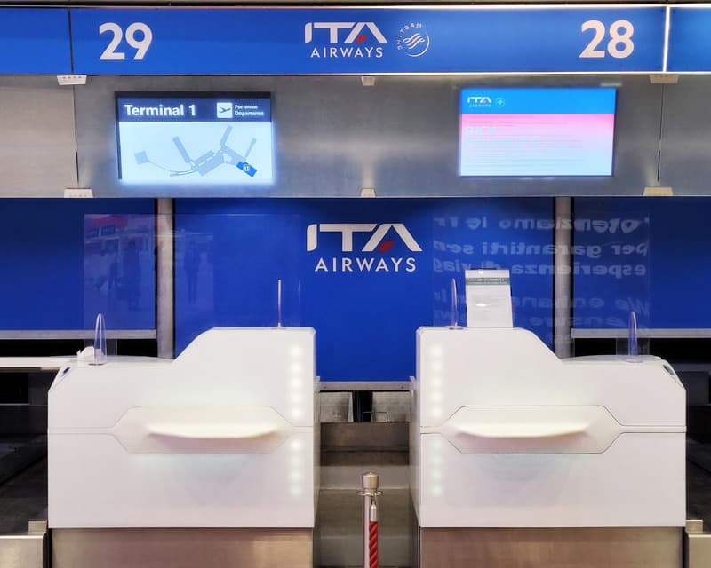 Two rebranded ITA Airways self-service check-in kiosks.