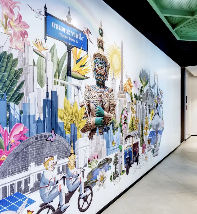 A floor-to-ceiling illustrated mural of Bangkok landmarks running the length of an office corridor