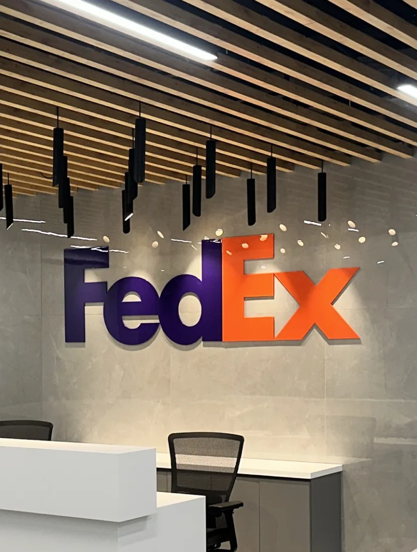 A FedEx wordmark in relief above a reception desk, under a slatted timber ceiling