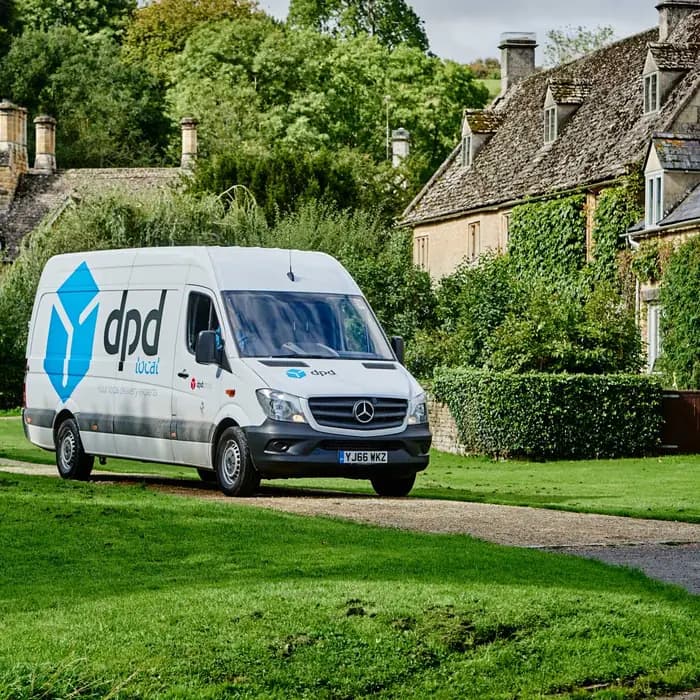 A dpd local delivery van parked outside cottages in the English countryside.