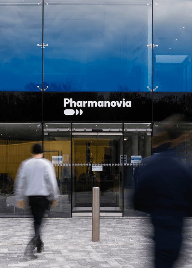 Pharmanovia signage above a glazed office entrance as staff walk past