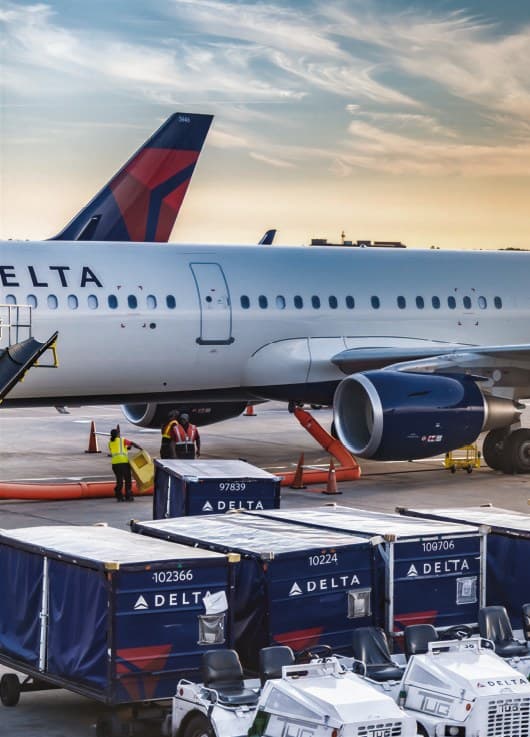 Delta aircraft and branded ground-handling containers on an airport apron