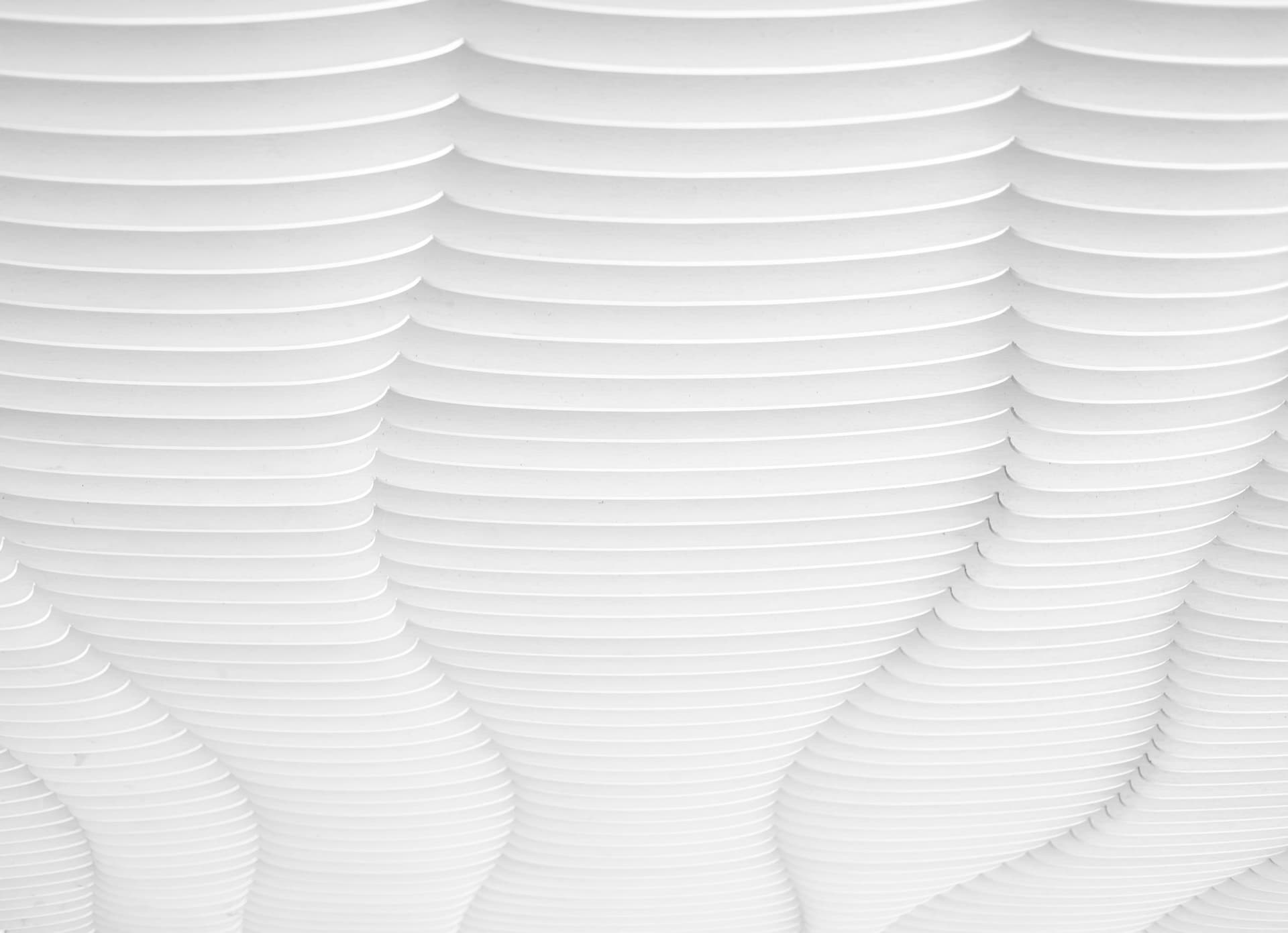 Overlapping white curved forms in a repeating relief pattern