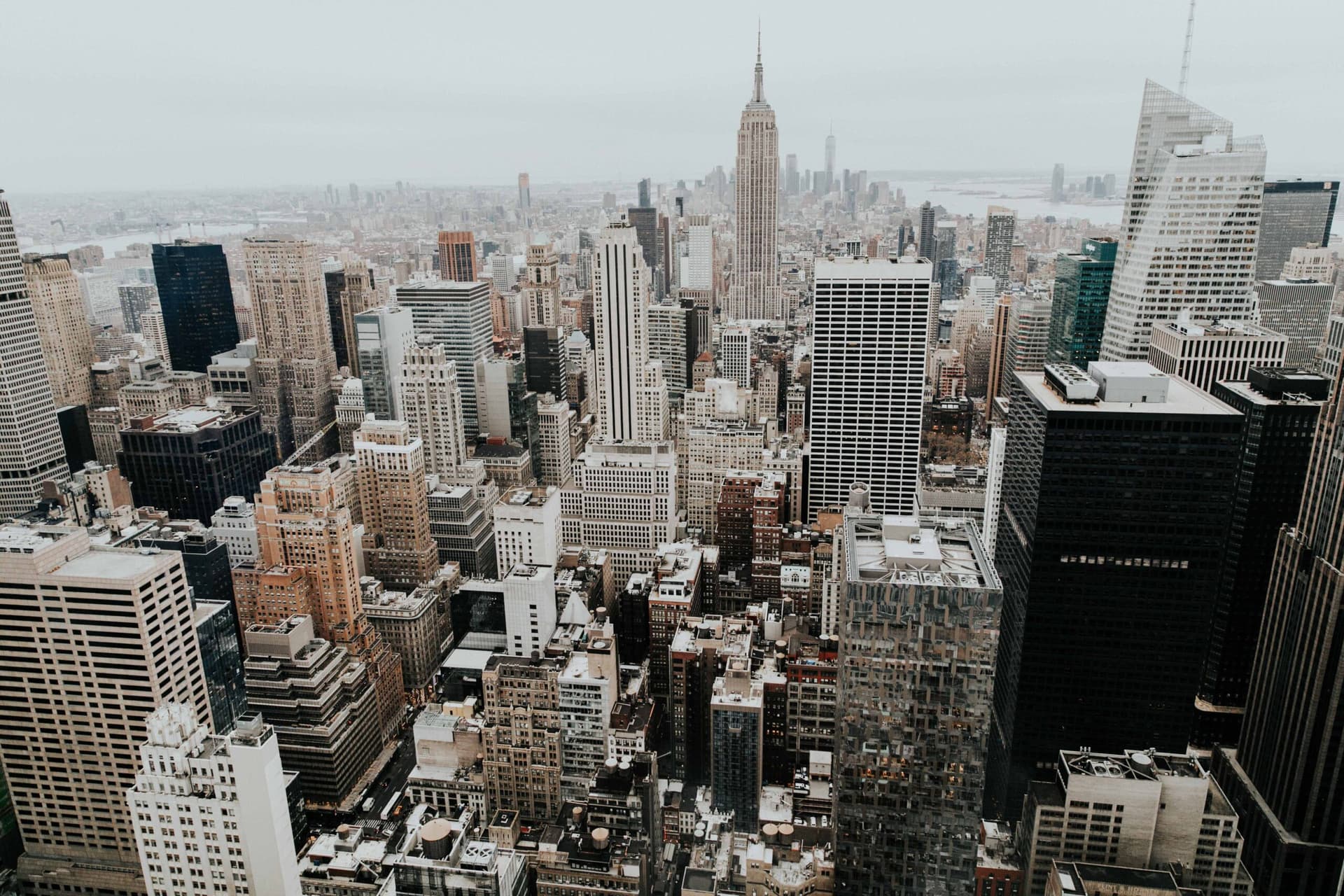 Aerial view of midtown Manhattan skyscrapers under a pale sky