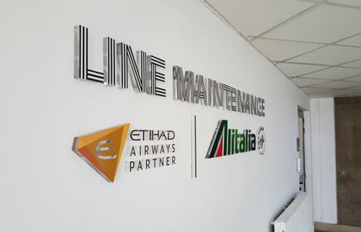 Line Maintenance signage with Etihad Airways Partner and Alitalia logos on an office wall