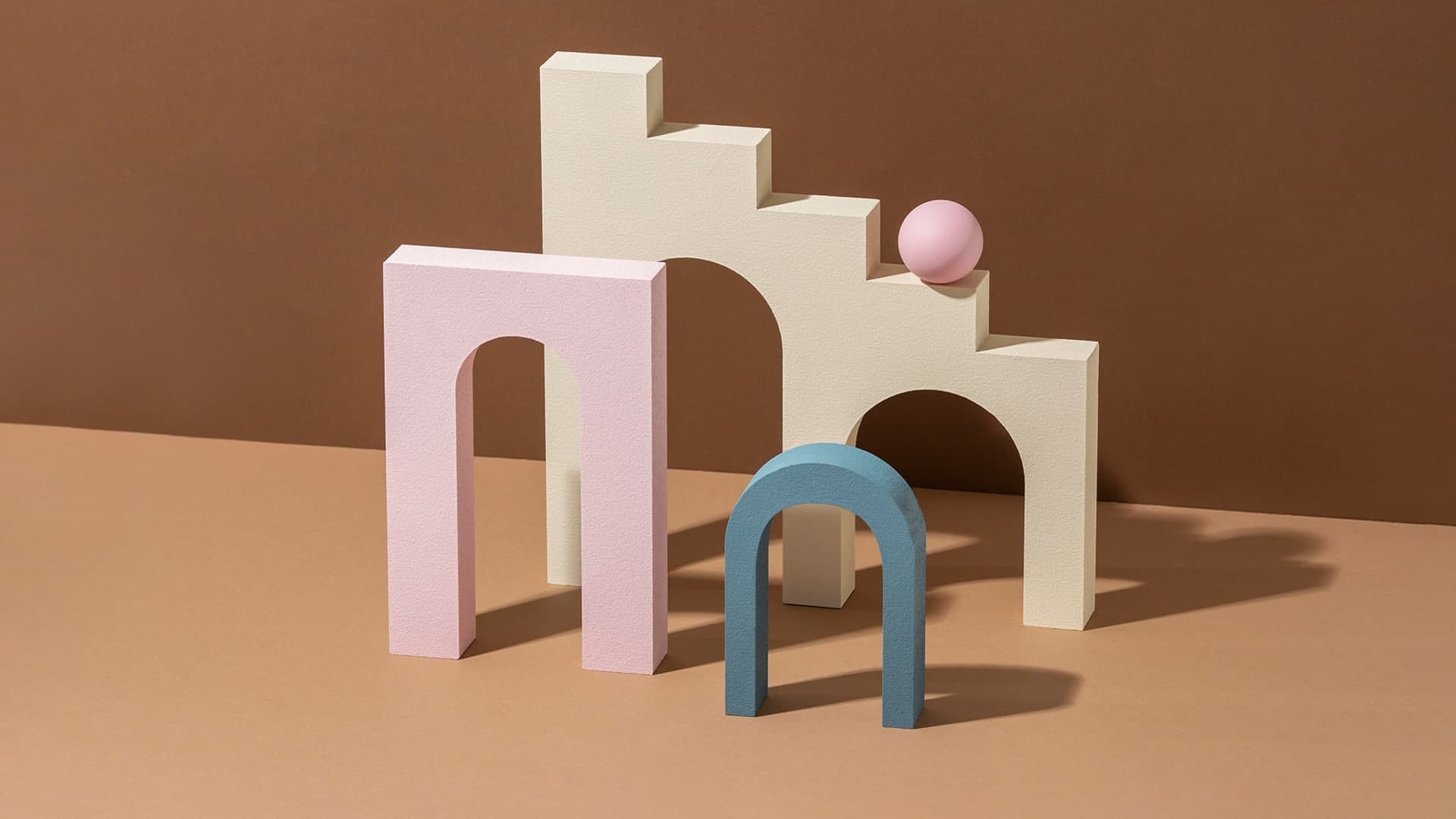Pastel arches and a sphere arranged as a still life on a brown background