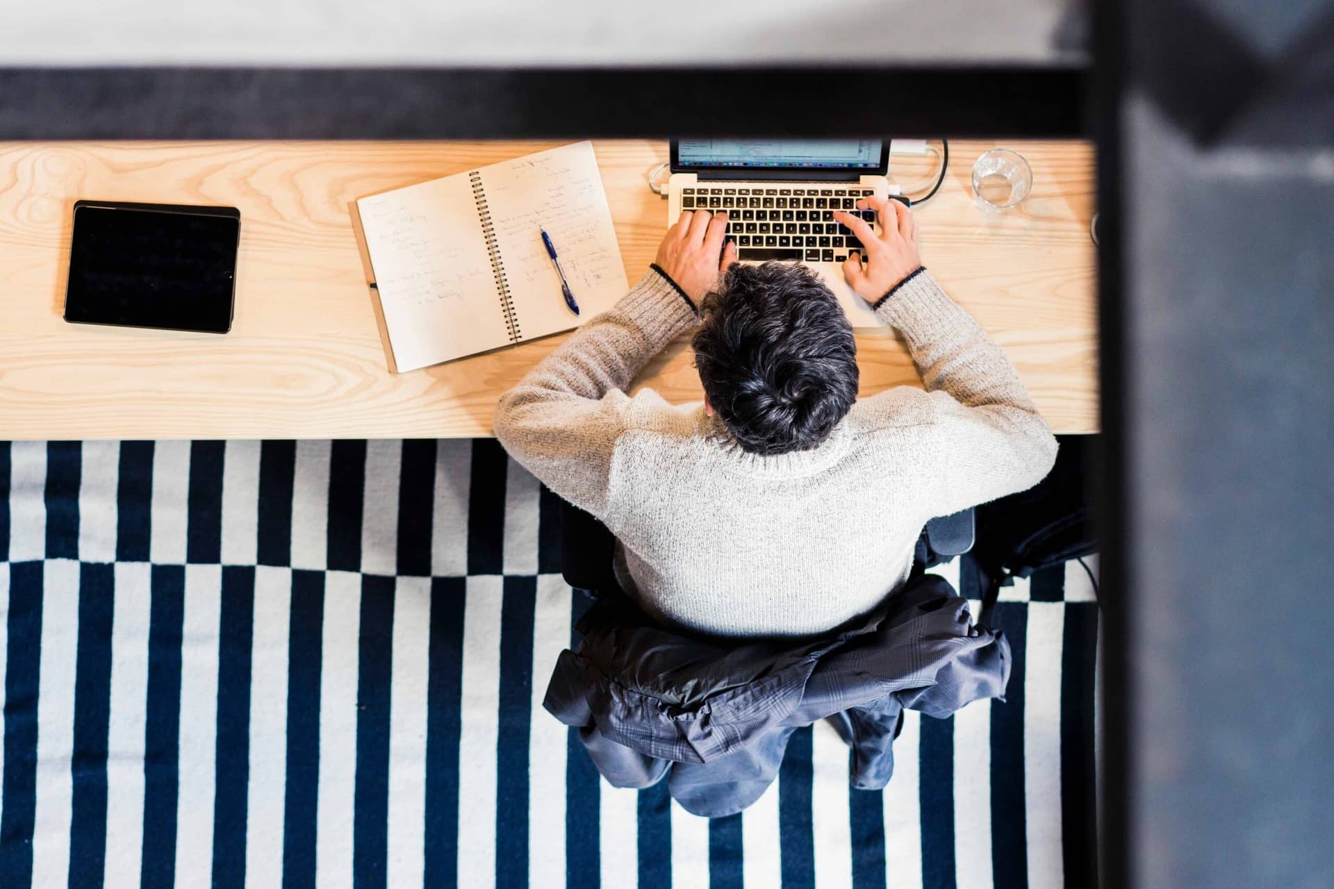 Overhead view of a person working at a laptop at a long wooden desk