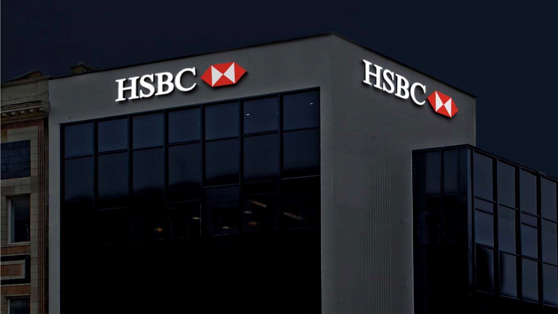 Illuminated HSBC signage on two faces of an office building at night