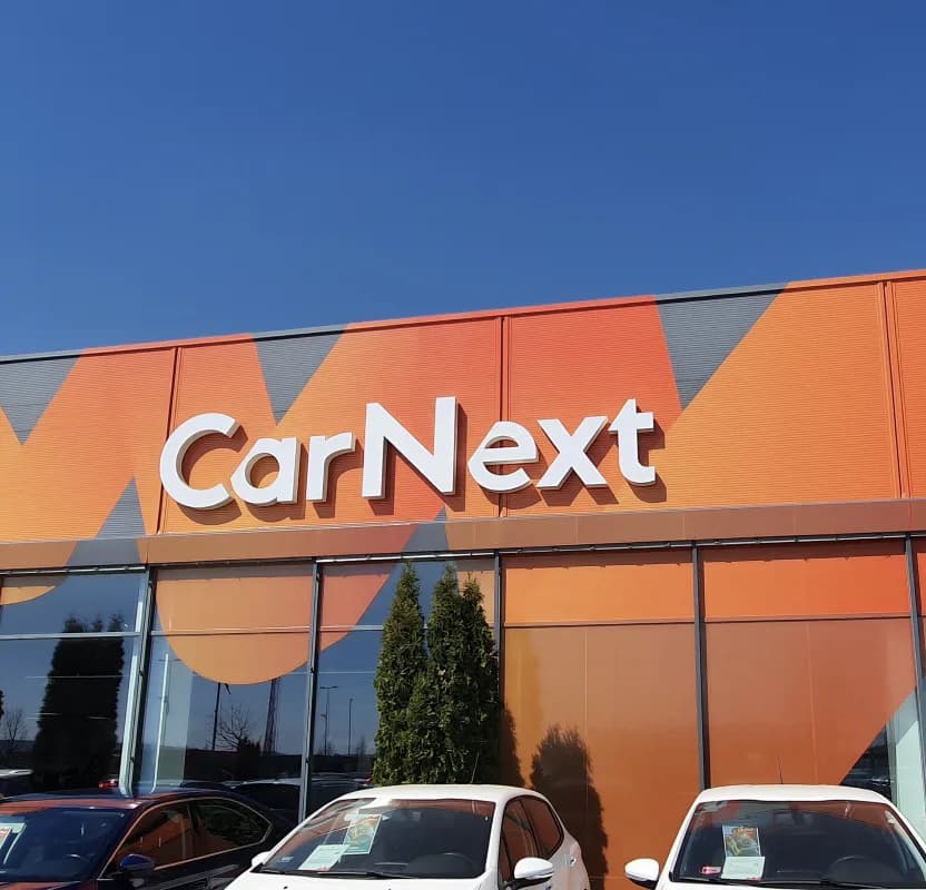 A CarNext showroom exterior with the brand fascia above a forecourt of cars