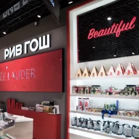 A beauty retail interior with backlit brand fascias above the product shelving