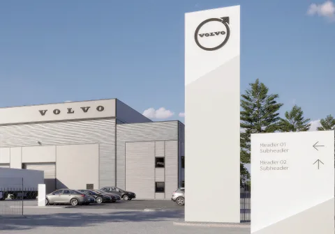 A Volvo dealership exterior beside a freestanding brand totem and a directional sign