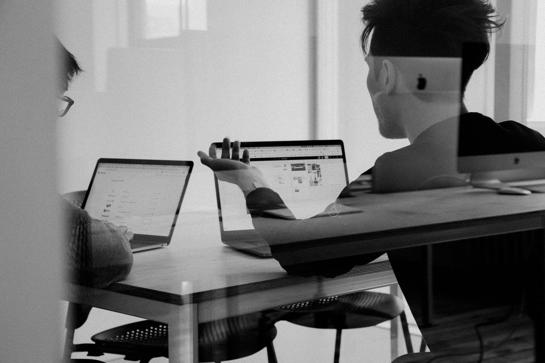 Two colleagues reviewing artwork together on laptops