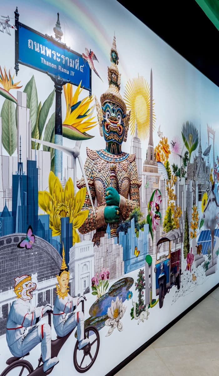 A large illustrated mural of Bangkok street signage and skyline covering an office corridor wall